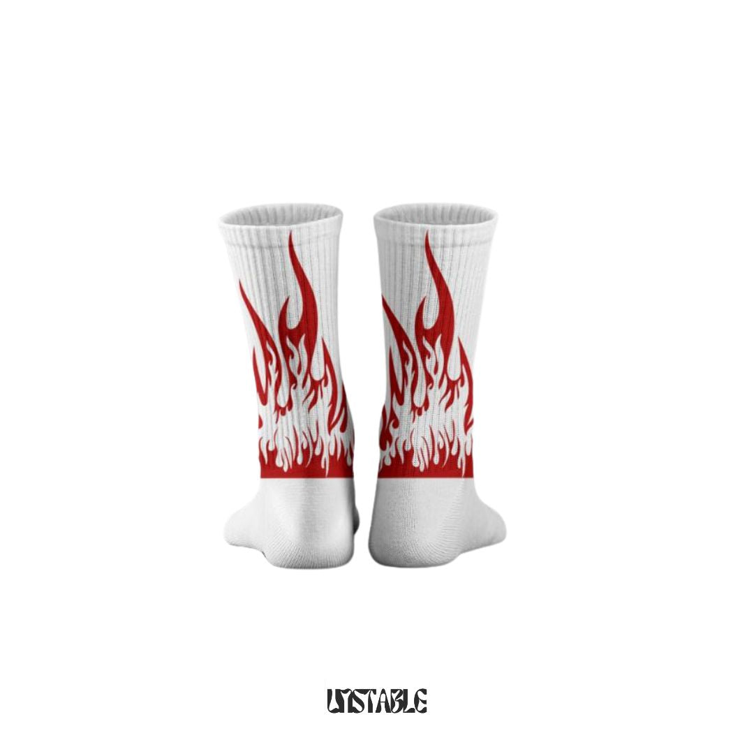 A pair of white heated flame patterned socks with red and black detailing, displayed against a plain background with the text 'UNSTABLE' at the bottom.