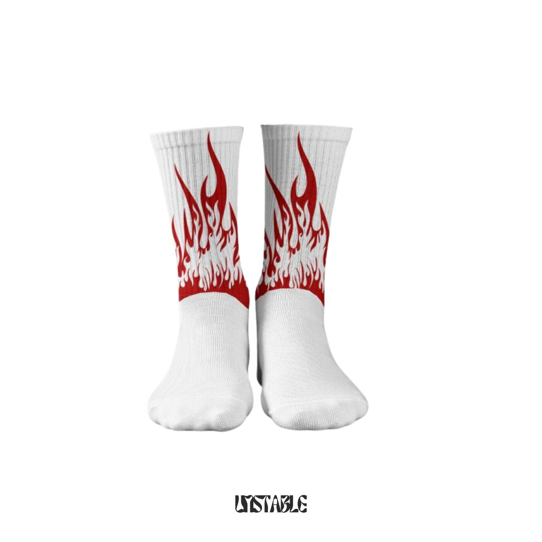 A pair of white heated flame patterned socks with red and black detailing, displayed against a plain background with the text 'UNSTABLE' at the bottom.